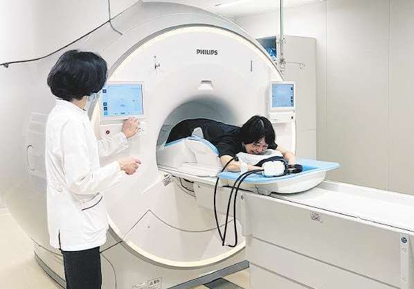 痛くない乳がん検査を受ける記者。うつぶせになり、足側から機械に入っていく＝愛知県安城市の安城更生病院で